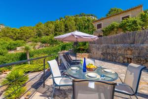 eine Terrasse mit Tisch, Sonnenschirm und Stühlen in der Unterkunft Cal Tio in Caimari