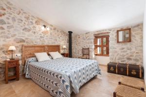 ein Schlafzimmer mit einem Bett und einer Steinwand in der Unterkunft Cal Tio in Caimari
