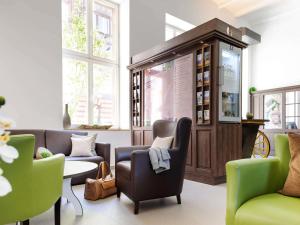a room with couches and chairs and a large cabinet at Ibis Styles Trier in Trier