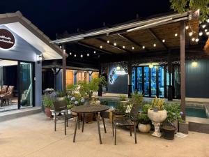a patio with a table and chairs and a pool at Baannaisuk Pool Villa in Ban Mae Pu Kha