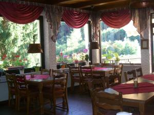 un comedor con mesas, sillas y ventanas en Hotel-Restaurant Burg-Ramstein, en Kordel