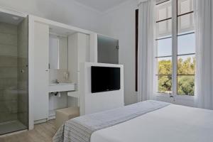 a white bedroom with a bed and a television at Prinsotel Mal Pas - Adults Only in Alcudia
