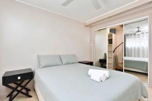 a white bedroom with a large bed and a mirror at Coal d' Vine Chillout - Cessnock NSW in Cessnock