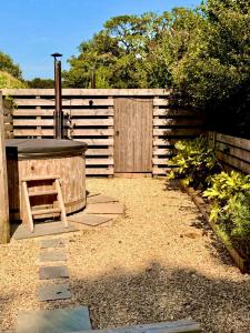 a backyard with a hot tub and a wooden fence at Arts Hollow in Binegar +3 photos