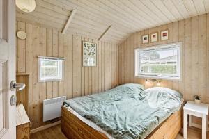 a bedroom with a bed in a room with wooden walls at 7323-Bogo-Vindrosen-23 in Gammelby