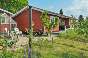 a red house with a garden and a grill at 8242-Vordingborg-Kvaedevej-8 in Bakkebølle Fredskov