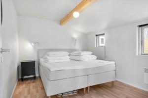 a white bedroom with a bed and a tv at 8242-Vordingborg-Kvaedevej-8 in Bakkebølle Fredskov