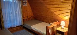 a small bedroom with a bed in a wooden wall at Vikendica Luna in Gornja Šišava