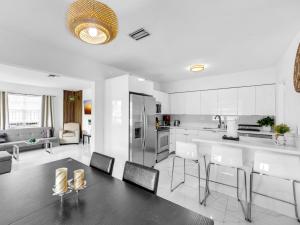 a kitchen with white cabinets and a table and chairs at Casa Playa Coastal Comfort 10 Min From Beach in Hallandale Beach