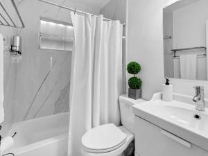 a white bathroom with a toilet and a sink at Casa Playa Coastal Comfort 10 Min From Beach in Hallandale Beach +13 photos