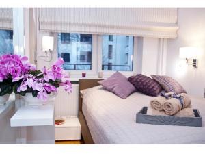 ワルシャワにあるSrebrna Warsaw Apartmentのベッドルーム1室(紫色の枕と花のベッド1台付)