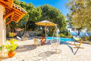 a patio with chairs and an umbrella and a pool at Villa Nionios in Vlachopoulátika