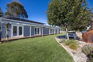 a house with a yard next to a building at Edelweiss Cottage in Berridale