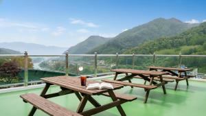 three picnic tables on a balcony with mountains in the background at gapyeong newcastle pension in Gapyeong