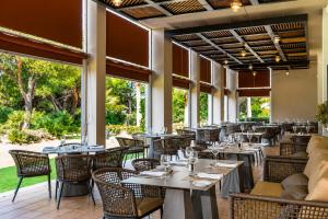 a restaurant with tables and chairs and large windows at Valentin Sancti Petri in Chiclana de la Frontera