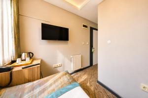 um quarto de hotel com uma televisão de tela plana na parede em Kavi Hotel em Istambul