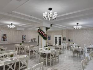 a dining room with white tables and white chairs at STATUS HOTEL in Qarshi