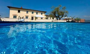 a swimming pool with blue water in front of a building at Oliveta del Tabernacolo in Malmantile