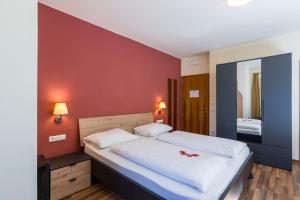 une chambre avec un grand lit blanc orné de fleurs rouges dans l'établissement Hotel Traube, à Bressanone