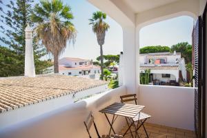 a balcony with a table and chairs and palm trees at Fernando Pessoa Villa in Faro