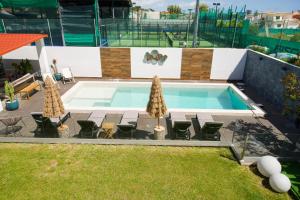 a pool with umbrellas and chairs next to at Fernando Pessoa Villa in Faro