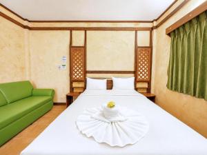 a bedroom with a large white bed with a green couch at Chalet De Palm Resort Hatyai in Hat Yai