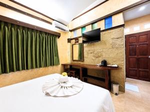 a bedroom with a bed and a desk and a television at Chalet De Palm Resort Hatyai in Hat Yai