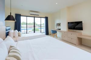 a bedroom with two beds and a flat screen tv at Aster Canopy Suites & Living in Rayong