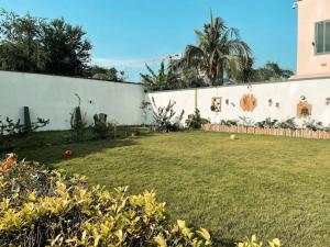 a yard with a white wall and a grass field at Tcc - Skysuites in Accra