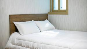 a bed with white sheets and a mirror in a room at Samcheok Eoulim Pension in Samcheok