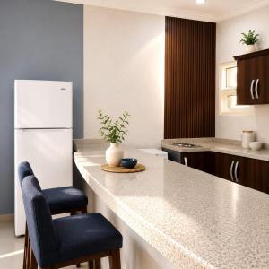 a kitchen with a white refrigerator and a counter with chairs at moon havena مون هافينا in Dhahran