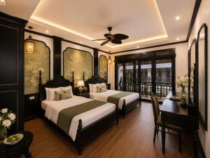 a bedroom with two beds and a desk and a ceiling fan at Luang Prabang Indochine Heritage Hotel in Luang Prabang