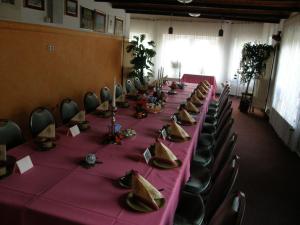 einen langen Tisch mit einem rosa Tischtuch und Stühlen in der Unterkunft KA&KA Hotel Garni in Warsow