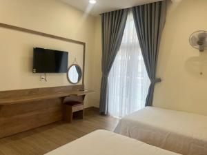 a hotel room with two beds and a flat screen tv at Minh's homestay in Long Bình