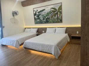 two beds in a room with white sheets at Minh's homestay in Long Bình