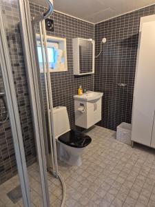a bathroom with a toilet with a black seat at Den fräscha lägenheten in Ängelholm