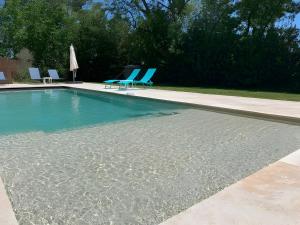 a swimming pool with two chairs and an umbrella at Studio charmant avec jardin in Saint-Rémy-de-Provence