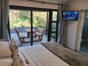 a bedroom with a bed and a television and a patio at Serenity Place B&B and Conference, wedding venue in Durban