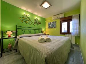 a green bedroom with a bed with two towels on it at Entrefrutales · Casa Rural entre Árboles y Aromas in La Vilueña