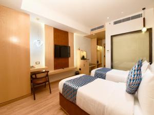a hotel room with two beds and a desk at Palette Hotel by CheckIn Amritsar, Airport Road in Amritsar