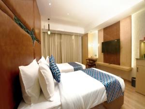 a hotel room with two beds and a flat screen tv at Palette Hotel by CheckIn Amritsar, Airport Road in Amritsar +52 photos