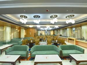 a restaurant with green couches and tables at Palette Hotel by CheckIn Amritsar, Airport Road in Amritsar