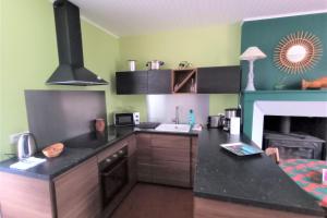 a kitchen with a black counter top and a fireplace at Gite cosy 4 pers en vallée de la Creuse in Baraize