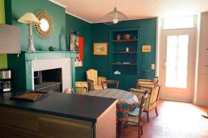 a kitchen with green walls and a table and chairs at Gite cosy 4 pers en vallée de la Creuse in Baraize