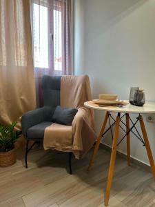 a chair with a blanket sitting next to a table at Breeze Apartments Megara - Nest in Megara +2 photos