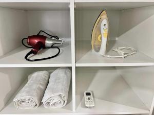 a shelf with a hair dryer a phone and towels at Edifício Madrid | Ayrton Senna in Toledo