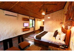 a bedroom with a bed and a desk and a television at Corbett Soho Resort in Haldwāni