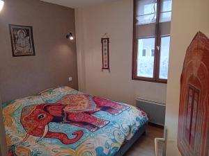 a bedroom with a bed with a colorful blanket at La Vie en Rose et Azur in Cluses