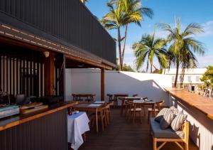 a patio with tables and chairs and palm trees at L'Escale Bleue in Saint-Leu