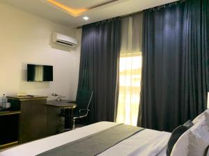 a hotel room with a bed and a desk and a window at Corporate Residence in Port Harcourt